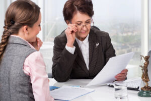 Woman looking at paperwork with another woman looking on - Eviction Defense Network