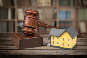 Gavel next to a small yellow house model